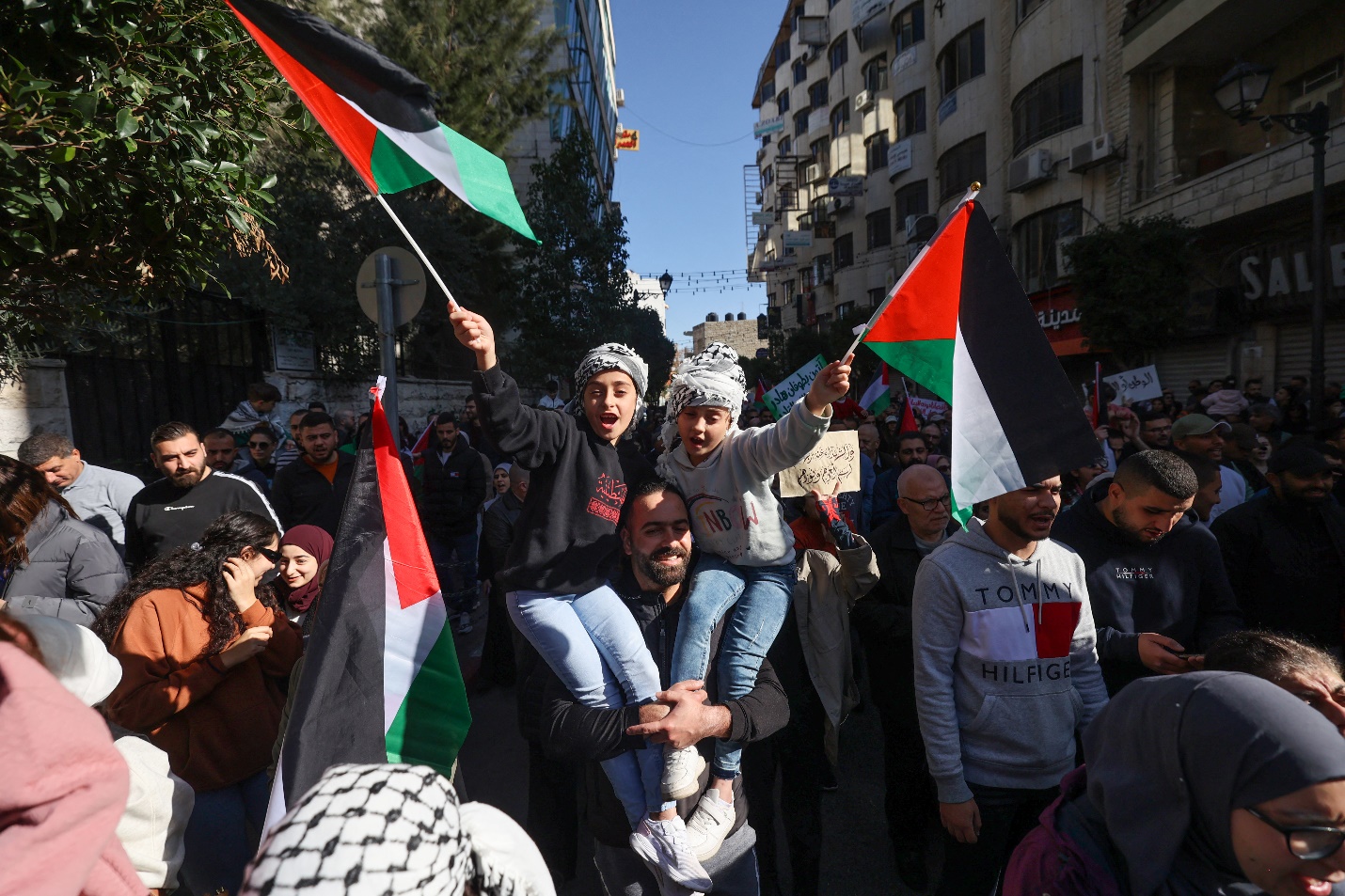 Palestinians wave their national flag and chant slogans during the general strike in Ramallah in the occupied West Bank on December 11, 2023 [Jaafar Ashtiyeh/AFP]