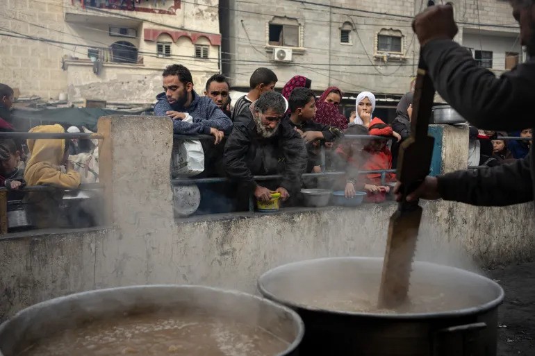 Palestinians line up for a meal provided by aid agencies in Rafah, the Gaza Strip [Fatima Shbair/AP Photo]